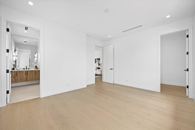 unfurnished bedroom featuring light hardwood / wood-style flooring, sink, and ensuite bathroom