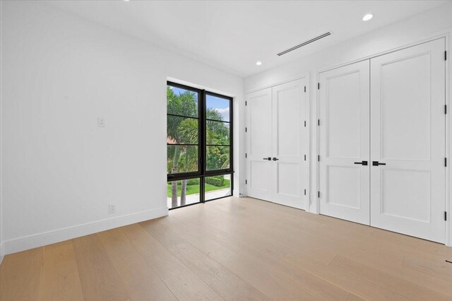 224 Edmor Rd, West Palm Beach, FL 33405 - unfurnished bedroom with two closets, wood finished floors, baseboards, recessed lighting, and access to exterior