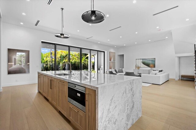 224 Edmor Rd, West Palm Beach, FL 33405 - kitchen featuring a sink, light wood finished floors, a spacious island, light stone counters, and recessed lighting