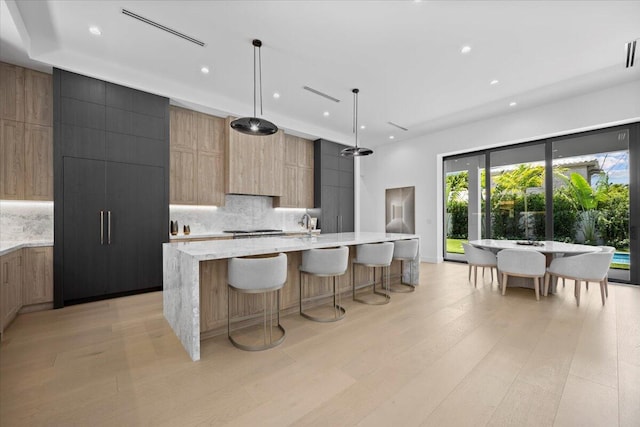 224 Edmor Rd, West Palm Beach, FL 33405 - kitchen with modern cabinets, backsplash, light wood-style floors, a large island with sink, and recessed lighting