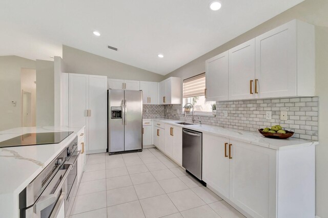 kitchen with white cabinetry, light stone countertops, appliances with stainless steel finishes, and lofted ceiling