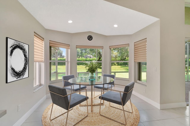 tiled dining area featuring vaulted ceiling