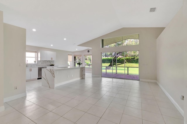 unfurnished living room featuring light tile patterned floors, plenty of natural light, baseboards, and lofted ceiling