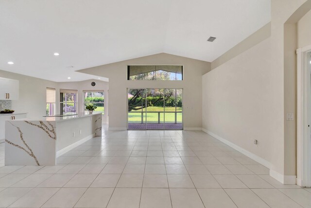 unfurnished living room featuring lofted ceiling and light tile patterned floors