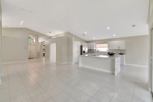 kitchen with stainless steel refrigerator with ice dispenser, backsplash, a center island, light tile patterned flooring, and white cabinetry