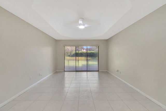 spare room featuring light tile patterned floors, ceiling fan, baseboards, and a tray ceiling