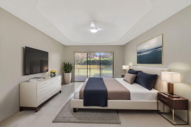 bedroom featuring ceiling fan, light tile patterned flooring, and a tray ceiling