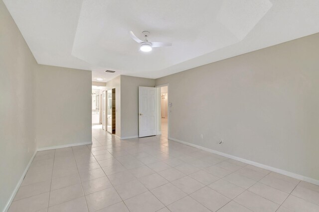 empty room featuring visible vents, light tile patterned floors, a ceiling fan, and baseboards