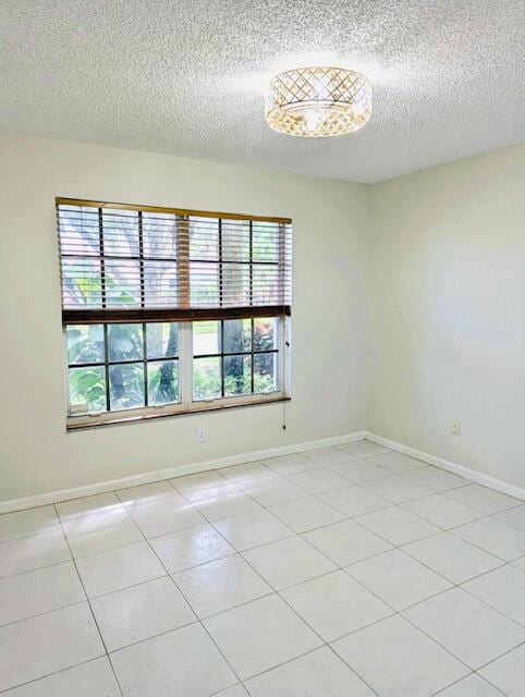 unfurnished room with a textured ceiling, a healthy amount of sunlight, and light tile patterned floors