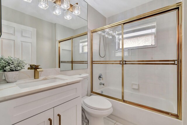 full bathroom with vanity, bath / shower combo with glass door, toilet, and tile patterned flooring