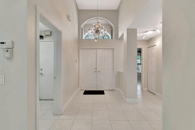 tiled entryway featuring a high ceiling and an inviting chandelier