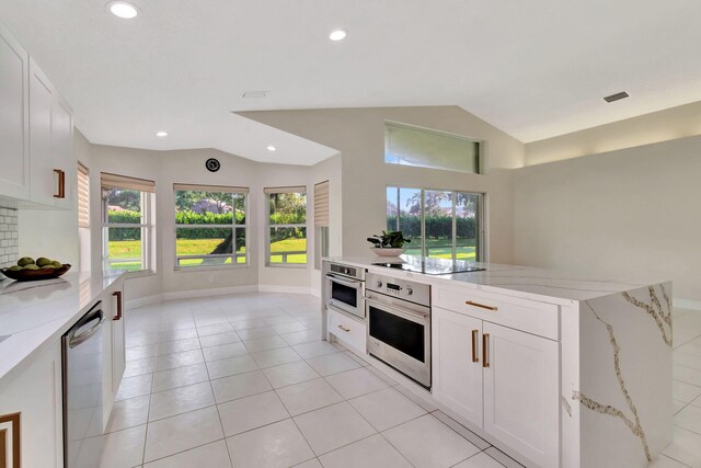 kitchen with light stone counters, appliances with stainless steel finishes, plenty of natural light, and white cabinets