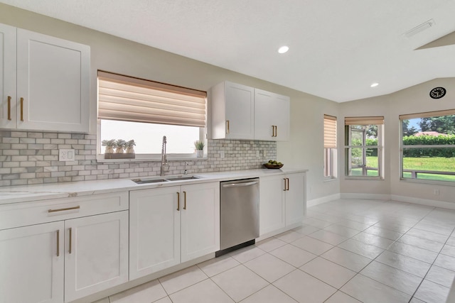 kitchen featuring a healthy amount of sunlight, lofted ceiling, stainless steel dishwasher, and white cabinets