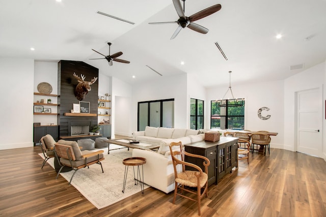 living room featuring a fireplace, vaulted ceiling, dark hardwood / wood-style floors, built in features, and ceiling fan