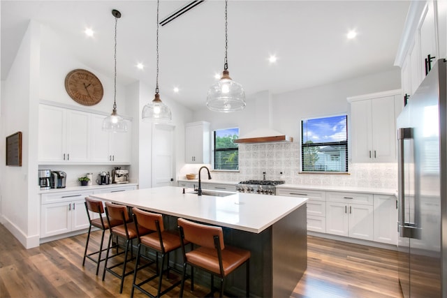 kitchen featuring hardwood / wood-style floors, appliances with stainless steel finishes, a kitchen island with sink, sink, and white cabinets