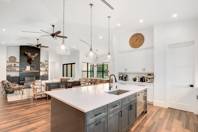 kitchen with white cabinets, light wood-type flooring, sink, an island with sink, and ceiling fan