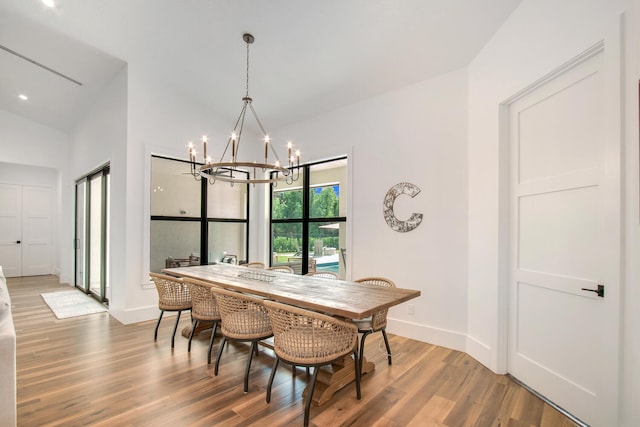 dining space featuring lofted ceiling, wood-type flooring, and an inviting chandelier