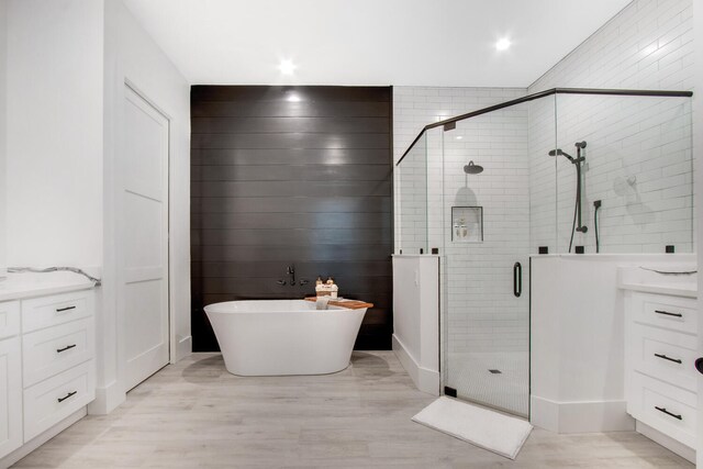 bathroom with plus walk in shower, hardwood / wood-style floors, and vanity