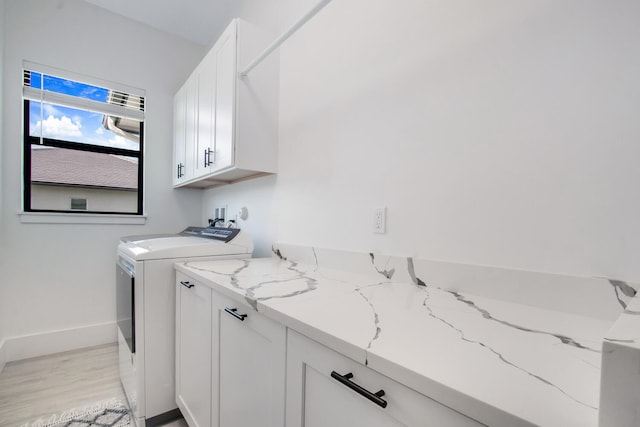 washroom with washer and dryer, cabinets, and light hardwood / wood-style flooring