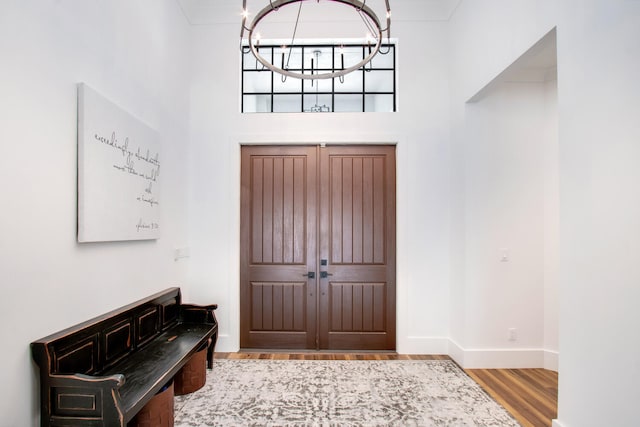 entrance foyer with light wood-type flooring, a chandelier, and a towering ceiling