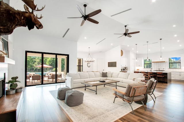 living room with high vaulted ceiling, ceiling fan with notable chandelier, and hardwood / wood-style flooring