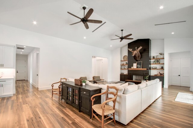 living room with a fireplace, vaulted ceiling, light hardwood / wood-style flooring, and ceiling fan