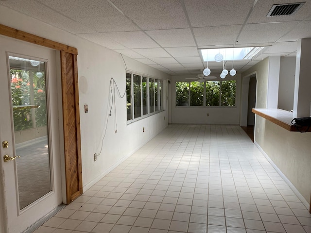 unfurnished sunroom with a skylight, plenty of natural light, and a drop ceiling