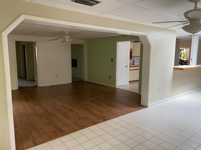 spare room with a paneled ceiling, ceiling fan, and light hardwood / wood-style floors