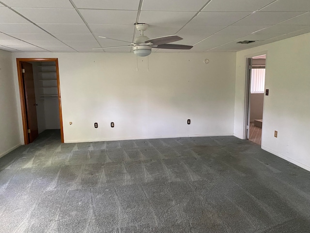 carpeted spare room featuring a drop ceiling and ceiling fan