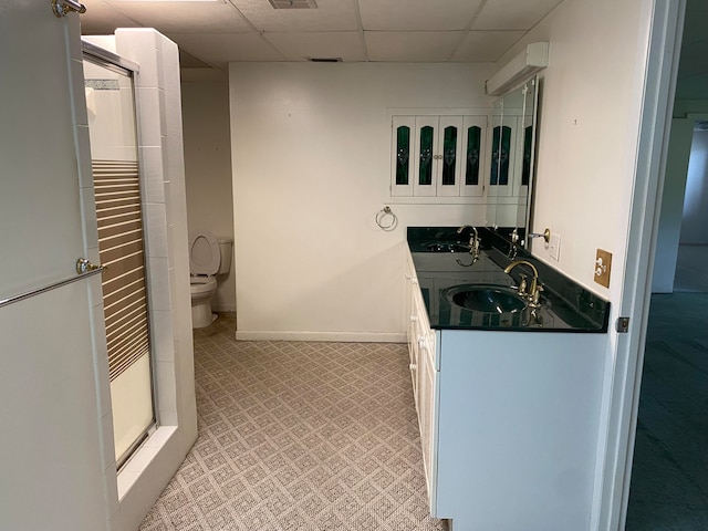 bathroom featuring vanity, toilet, and a drop ceiling