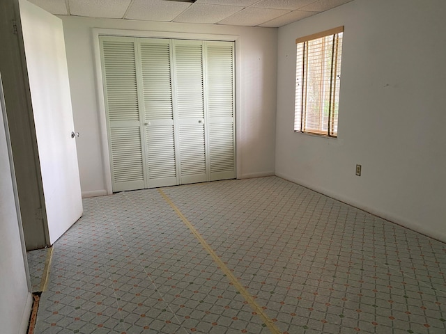 unfurnished bedroom with a paneled ceiling, carpet flooring, and a closet