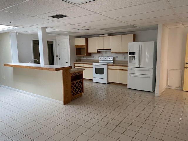 kitchen featuring decorative backsplash, cream cabinets, white appliances, and a paneled ceiling