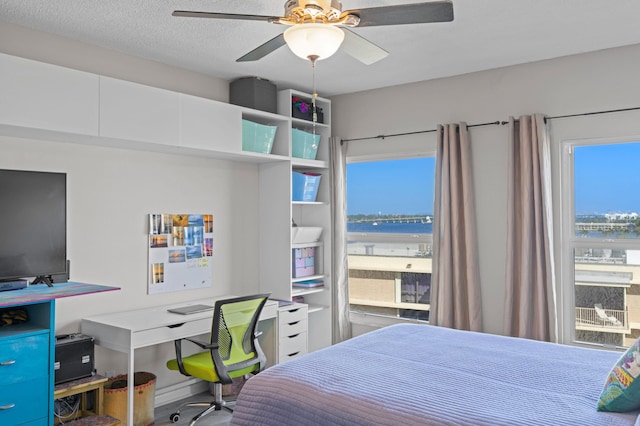 bedroom featuring a textured ceiling, a water view, and ceiling fan