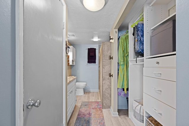 bathroom with walk in shower, hardwood / wood-style floors, vanity, and toilet