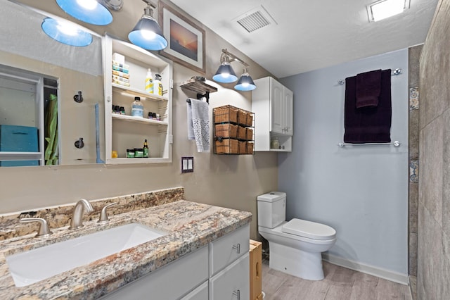 bathroom featuring vanity, wood-type flooring, a textured ceiling, and toilet