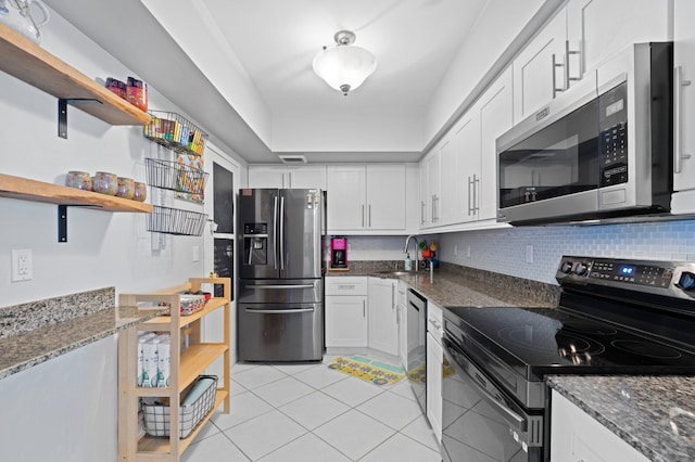 kitchen featuring dark stone countertops, decorative backsplash, white cabinets, and stainless steel appliances