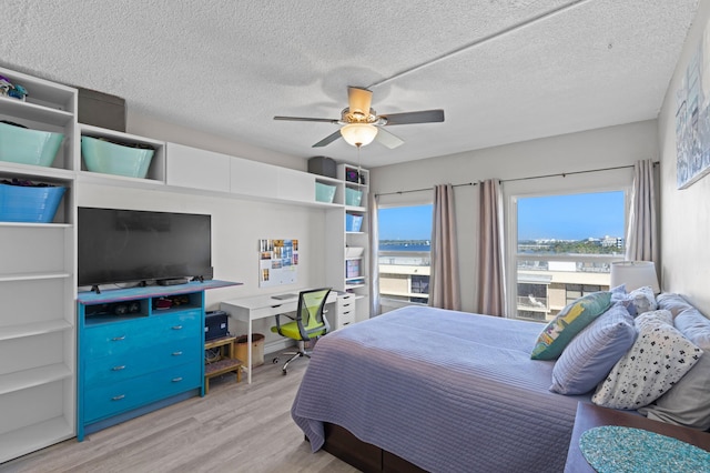 bedroom featuring a textured ceiling, light wood-type flooring, and ceiling fan