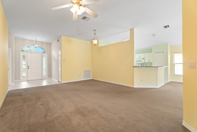 unfurnished living room featuring a textured ceiling, ceiling fan, and light carpet