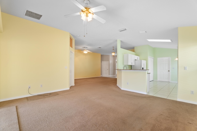 unfurnished living room with vaulted ceiling, light colored carpet, and ceiling fan