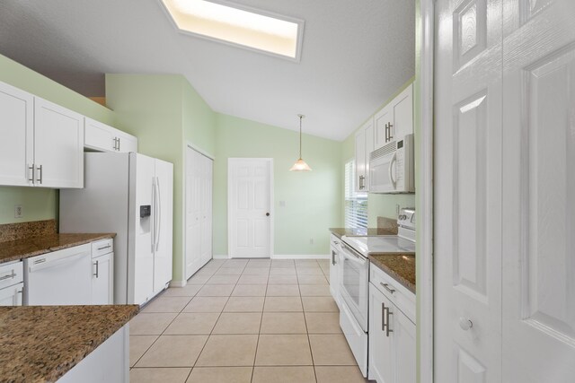 kitchen featuring lofted ceiling, white appliances, dark stone counters, and white cabinetry