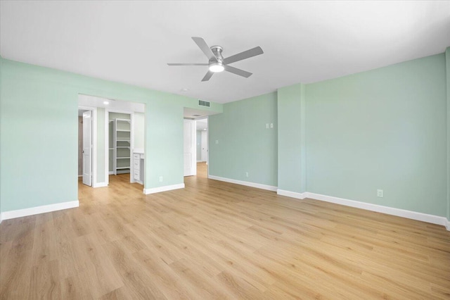 unfurnished bedroom featuring a closet, a spacious closet, ceiling fan, and light hardwood / wood-style floors