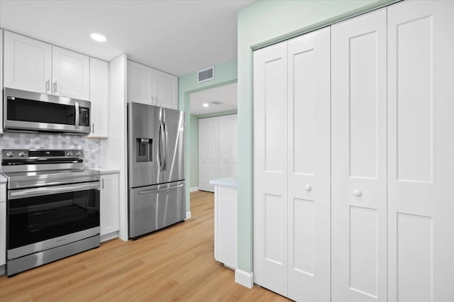 kitchen featuring light hardwood / wood-style flooring, stainless steel appliances, white cabinets, and tasteful backsplash