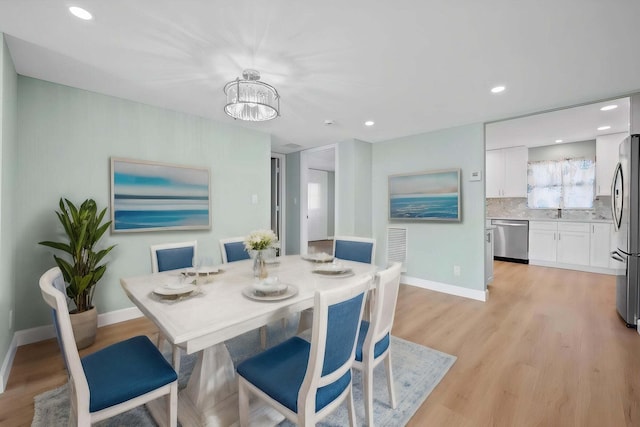 dining room with sink, a notable chandelier, and light hardwood / wood-style floors