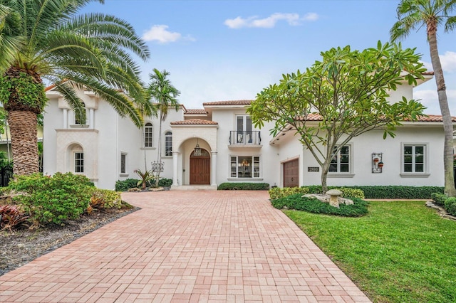 mediterranean / spanish house featuring a front yard and a balcony