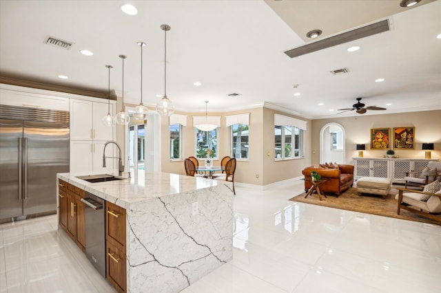 kitchen with sink, light stone counters, pendant lighting, a spacious island, and appliances with stainless steel finishes