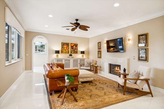 tiled living room featuring ceiling fan, a high end fireplace, and ornamental molding