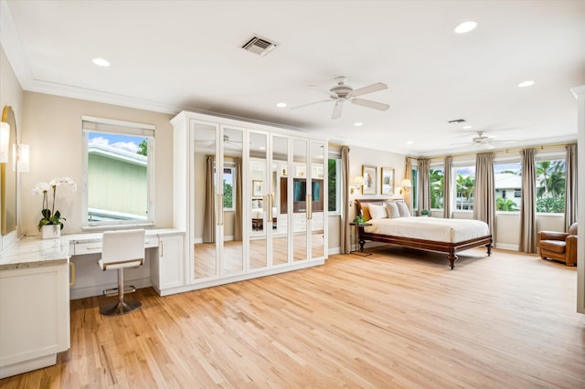 bedroom featuring light wood-type flooring, built in desk, ceiling fan, and crown molding