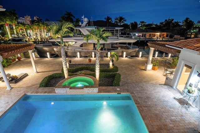 pool at night with an in ground hot tub and a patio