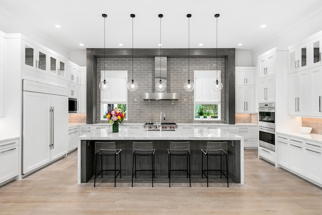 kitchen featuring a center island with sink, appliances with stainless steel finishes, a kitchen bar, and light hardwood / wood-style flooring