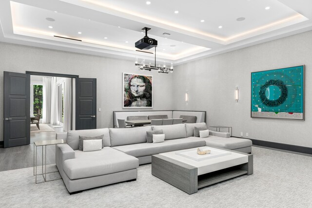 home theater featuring a raised ceiling, a chandelier, and hardwood / wood-style floors